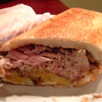 The pork of the Sazon sandwich with fries /El puerco del Sazon con papas fritas